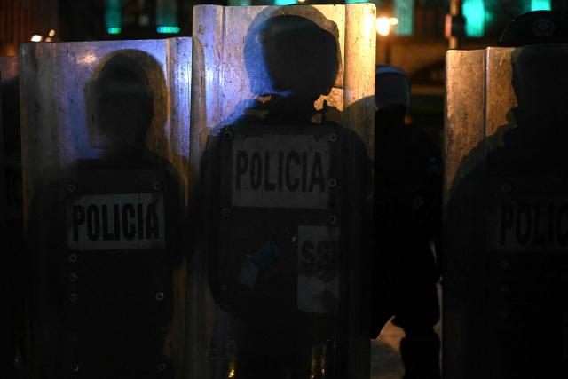 Riot police silhouettes are pictured during a rally commemorating the 57th anniversary of the 1968 Tlatelolco student massacre in Mexico City on October 2, 2025. (Photo by Yuri CORTEZ / AFP)