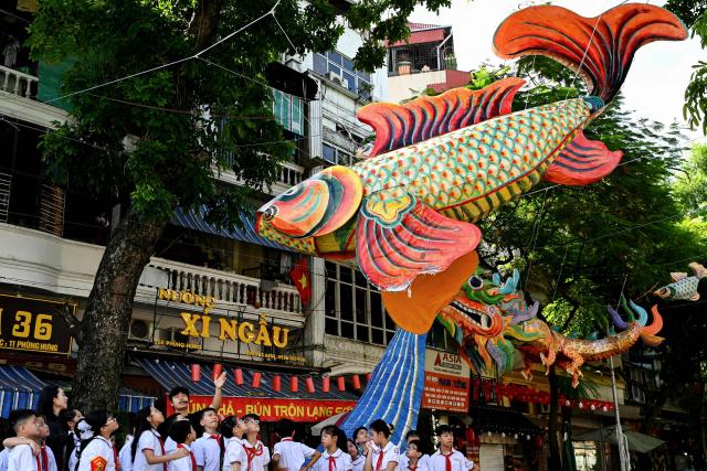Primary school students listen to an introduction about street lanterns in Hanoi's Old Quarter on October 3, 2025. (Photo by Nhac NGUYEN / AFP)