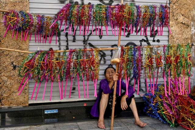A woman selling lanterns waits for customers on a pavement in Hanoi's Old Quarter on October 3, 2025. (Photo by Nhac NGUYEN / AFP)