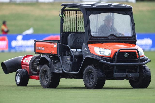 Ground staff attempt to dry the outfield during the second Twenty20 cricket match between New Zealand and Australia at Bay Oval in Mount Maunganui on October 3, 2025. (Photo by Aaron Gillions / AFP)