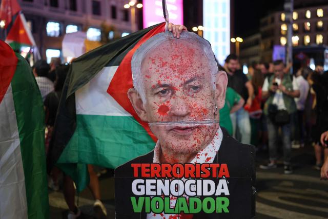 A protester holds a defaced poster depicting Israeli Prime Minister Benjamin Netanyahu with the words "Terrorist, Genocidal, Rapist" during a demonstration in solidarity with the Palestinians in the Gaza strip, in Madrid on October 4, 2025. The Global Sumud Flotilla, with around 45 vessels carrying politicians and activists, departed Barcelona last month to challenge Israels blockade of Gaza, where the United Nations reports famine conditions after nearly two years of war. The Israeli navy intercepted several vessels at sea on October 1, 2025, after warning activists against entering waters it says fall under its blockade. (Photo by Thomas COEX / AFP)