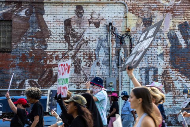Protesters march by a civil rights mural in Memphis, Tennessee, in opposition to the increase of federal law enforcement agents, the coming deployment of the National Guard and xAI, an AI company owned by Elon Musk that is locally based, during the "Get Out of Memphis" protest on October 4, 2025. Over the past week the city of Memphis has seen a dramatic increase in federal law enforcement as the Trump administration pledges to fight crime in the city. The protest was organized by Tigers Against Pollution, a student led activist group based in Memphis. (Photo by Austin Johnson / AFP)
