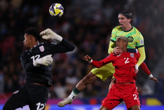 Australia's defender #02 Daniel Bennie (C) and Cuba's defender #02 Elvis Casanova (R) fight for the ball past Cuba's goalkeeper #12 Yurdy Hodelin during the 2025 FIFA U-20 World Cup football match between Australia and Cuba at the National Stadium in Santiago on October 4, 2025. (Photo by Javier TORRES / AFP)