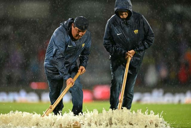 Pumas' field staff remove water from the pitch ahead of the Liga MX Apertura tournament football match between Pumas and Guadalajara at the Olimpico Universitario Stadium in Mexico City on October 5, 2025. (Photo by Yuri CORTEZ / AFP)