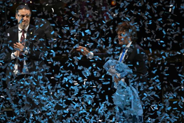 Argentina's President Javier Milei (R) greets supporters next to Presidency Spokesman and legislative candidate Manuel Adorni during the launch of his new book, "The Making of the Miracle," at the Movistar Arena in Buenos Aires on October 6, 2025. (Photo by Luis ROBAYO / AFP)