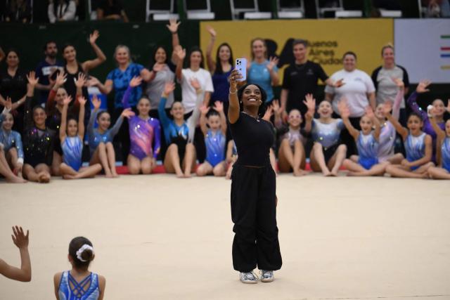 US Olympic gymnast Simone Biles takes a selfie photo during a gymnastics clinic at the Mary Teran de Weiss Stadium in Buenos Aires on October 9, 2025. (Photo by LUIS ROBAYO / AFP)