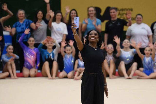 US Olympic gymnast Simone Biles takes a selfie photo during a gymnastics clinic at the Mary Teran de Weiss Stadium in Buenos Aires on October 9, 2025. (Photo by LUIS ROBAYO / AFP)