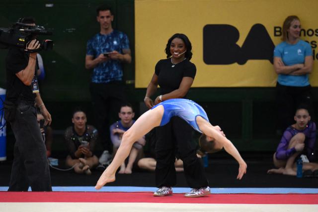US Olympic gymnast Simone Biles looks at a young gymnast performing during a gymnastics clinic at the Mary Teran de Weiss Stadium in Buenos Aires on October 9, 2025. (Photo by LUIS ROBAYO / AFP)
