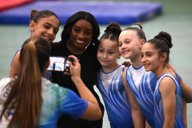 US Olympic gymnast Simone Biles poses for a picture with young gymnasts during a gymnastics clinic at the Mary Teran de Weiss Stadium in Buenos Aires on October 9, 2025. (Photo by LUIS ROBAYO / AFP)