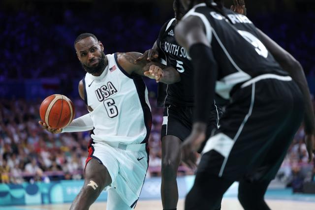 (FILES) USA's #06 LeBron James challenges South Sudan's #05 Nuni Omot in the men's preliminary round group C basketball match between USA and South Sudan during the Paris 2024 Olympic Games at the Pierre-Mauroy stadium in Villeneuve-d'Ascq, northern France, on July 31, 2024. Los Angeles superstar LeBron James is set to miss the Lakers' NBA season-opener after the team said he will be sidelined three to four weeks with sciatica, multiple US media outlets reported on October 9, 2025. The Lakers revealed the diagnosis of right-side sciatica after the team's practice, where the 40-year-old James again was not a full participant. (Photo by Thomas COEX / AFP)