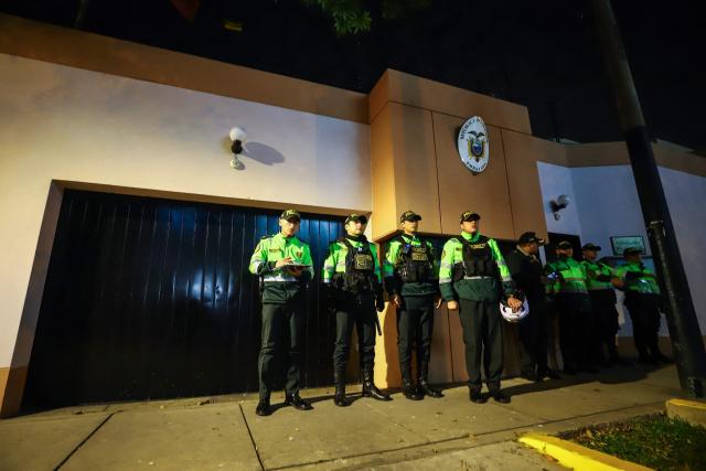 Police officers stand guard in front of the Ecuador embassy during a protest against President Dina Boluarte after the congress approved four motions of impeachment against the Peruvian in Lima on October 9, 2025. Peru's main political forces presented four motions to Congress on Thursday calling for President Dina Boluarte to be impeached in light of the severe security crisis, according to documents filed in plenary session. (Photo by Jorge CERDAN / AFP)