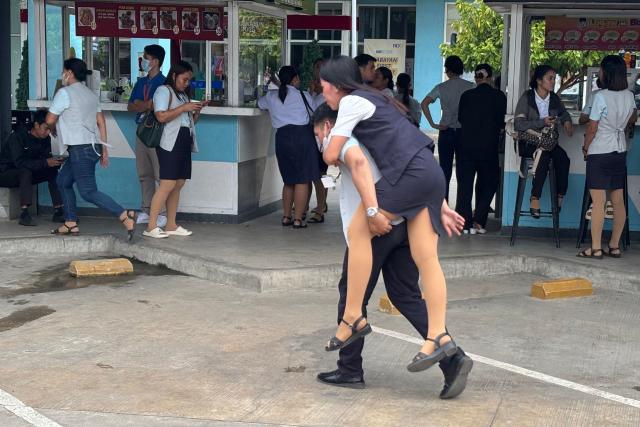 An employee at a mall carries a colleague after she slipped while evacuating a building in Butuan City, on the southern island of Mindanao on October 10, 2025, after a 7.4-magnitude earthquake struck off the southern Philippines. A powerful magnitude-7.4 earthquake struck off the southern Philippines on October 10, triggering warnings of a "destructive tsunami" on the country's Pacific coast within hours. (Photo by Erwin MASCARINAS / AFP)