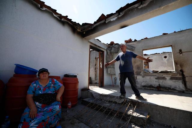 Kujtim Palloshi and his wife Mimoza cle in Skenderbegas, near Gramsh, on September 16, 2025. Weeks of violent wildfires have devastated pine forests around Skenderbegas in central Albania’s Gramsh region, destroying more than 700 hectares of woodland and dozens of homes with livestock and wildlife among the victims, as the country faced extreme heat and drought on summer 2025, making it one of the Balkan nations most affected by wildfires. (Photo by Adnan Beci / AFP)