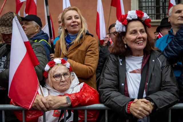 A woman looks on as she holds Poland's national flag during an anti-migration protest called by Poland's nationalist Law and Justice (PiS) party on the Royal Castle Square in Warsaw, Poland, October 11, 2025. Thousands of supporters gathered on Warsaw's Old Town to express their disagreement with illegal migration and EU Migration Pact but also to protest against the politics of Poland's Prime Minister Donald Tusk, and the Eu-Mercosur Free trade agreement. (Photo by Wojtek RADWANSKI / AFP)
