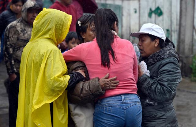 A woman is comforted after noticing that her belongings will be removed from her damaged home in the municipality of Huauchinango, Puebla State, Mexico on October 11, 2025. The death toll from heavy rains in Mexico rose to 37 on Saturday after nine more fatalities were confirmed, the Mexican government reported. (Photo by Alfredo ESTRELLA / AFP)
