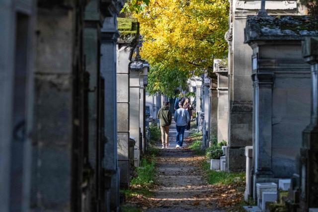 Visitors walk between graves at the Pere Lachaise cemetery park in Paris on October 12, 2025. (Photo by Martin LELIEVRE / AFP)