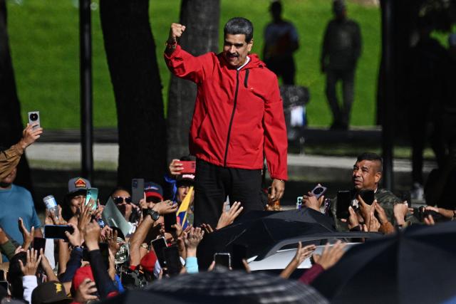 Venezuela's President Nicolas Maduro waves to supporters during a march to commemorate the "Day of Indigenous Resistance" in Caracas on October 12, 2025. On Sunday, Venezuelan President Nicolбs Maduro called opposition leader Marнa Corina Machado a “demonic witch,” two days after she was awarded the Nobel Peace Prize. (Photo by Federico PARRA / AFP)