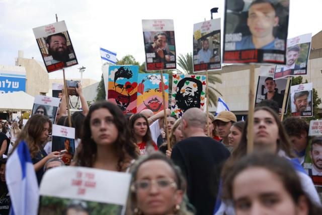 People holding up portraits of Israeli hostages still held in Gaza gather at Hostage Square in Tel Aviv early on October 13, 2025. Hamas was set to release all surviving hostages on on October 13 in exchange for Palestinian prisoners held by Israel, as US President Donald Trump headed to the region for a peace summit having declared the war "over". Trump's lightning visit to Israel and Egypt aims to celebrate his role in brokering last week's ceasefire and hostage release deal -- but comes at a precarious time as Israel and Hamas negotiate what comes next. (Photo by Menahem KAHANA / AFP)