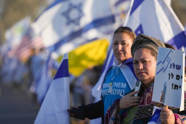 Flag-waving Israelis gather outside the Reim military base near the border with Gaza in southern Israel on October 13, 2025 to welcome the hostages about to arrive following their release by Hamas from the Gaza Strip. Hamas was set to release all surviving Israeli hostages on October 13 in exchange for Palestinian prisoners held by Israel, as US President Donald Trump headed to the region for a peace summit having declared the war "over". Trump's lightning visit to Israel and Egypt aims to celebrate his role in brokering last week's ceasefire and hostage release deal -- but comes at a precarious time as Israel and Hamas negotiate what comes next. (Photo by MAYA LEVIN / AFP)