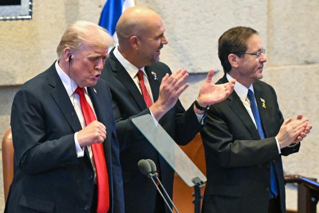 US President Donald Trump (L) reacts next to Amir Ohana (2nd L), Speaker of the Israeli Knesset, and Israeli President Isaac Herzog as he receives a standing ovation before speaking at the Israeli parliament, the Knesset, in Jerusalem on October 13, 2025. Hamas handed over the 20 surviving Israeli hostages on October 13 under a ceasefire agreement, as the US president and other world leaders geared up for a summit on Gaza. The releases are part of a ceasefire agreement brokered by the US president, with Israel due in return to free nearly 2,000 detainees held in its jails in exchange. (Photo by Kenny HOLSTON / POOL / AFP)