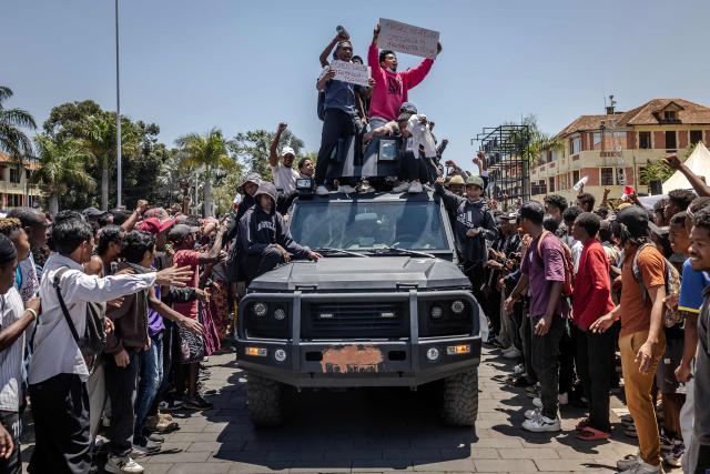 Students and protesters ride atop a Malagasy Army patrol vehicle holding banners and chanting anti-government slogans as residents gather for a civil society rally outside City Hall in Antananarivo, on October 13, 2025. Soldiers and security forces joined hundreds celebrating in Madagascar's capital on October 13, 2025, hours before President Andry Rajoelina was due to address the nation following weeks of protests and growing calls for his resignation. (Photo by Luis TATO / AFP)