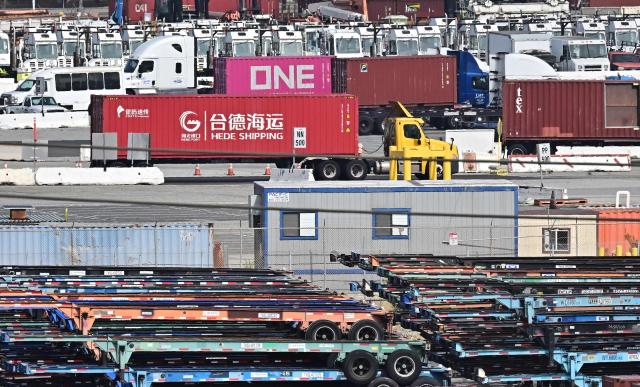 A container truck from Hede Shipping, from the Chinese state-owned Hebei Port Group, passes a row of flatbed trailers at the Port of Los Angeles in Los Angeles, California on October 13, 2025. President Donald Trump said October 12, 2025 the United States wants to help China, not hurt it, striking a conciliatory tone days after threatening an additional 100 percent tariff on the world's second-largest economy. Trump's statements on October 10 as well as his threat to cancel a meeting with Xi later this month sent Wall Street stocks tumbling into negative territory as traders worried the trade war between Washington and Beijing could reignite. (Photo by Frederic J. BROWN / AFP)