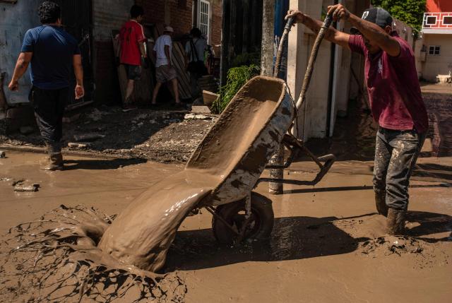 A man uses a wheelbarrow to remove mud from his home after severe flooding hit the city of Alamo, in Veracruz state, Mexico, on October 13, 2025. The death toll from flooding in central and eastern Mexico -mostly in the Veracruz, Hidalgo and Puebla states- has risen sharply to at least 64, with another 65 still missing, authorities reported. (Photo by Hector  Quintanar / AFP)
