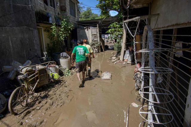 Men wade through mud after severe flooding hit the town of Alamo, in Veracruz state, Mexico, on October 13, 2025. The death toll from flooding in central and eastern Mexico -mostly in the Veracruz, Hidalgo and Puebla states- has risen sharply to at least 64, with another 65 still missing, authorities reported. (Photo by Marco Antonio Perez / AFP)