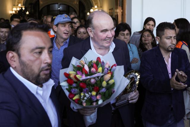 Rafael Lopez Aliaga (C), holding a bouquet of flowers, leaves Lima City Hall after announcing his resignation as mayor to run for president in Lima on October 13, 2025. Lima's ultraconservative mayor Rafael Lopez Aliaga announced his resignation on Monday to run for president in Peru's general elections scheduled for April 2026. (Photo by CONNIE FRANCE / AFP)