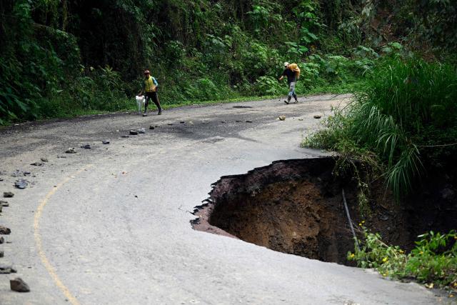 Locals walk along the Tenango de Doria–San Bartolo Tutotepec road after heavy rains caused severe damage in Hidalgo state, Mexico, on October 13, 2025. The death toll from flooding in central and eastern Mexico -mostly in the Veracruz, Hidalgo and Puebla states- has risen sharply to at least 64, with another 65 still missing, authorities reported. (Photo by Alfredo ESTRELLA / AFP)
