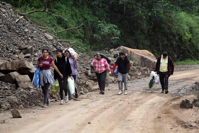 Locals walk along the Tenango de Doria–San Bartolo Tutotepec road after heavy rains caused severe damage in Hidalgo state, Mexico, on October 13, 2025. The death toll from flooding in central and eastern Mexico -mostly in the Veracruz, Hidalgo and Puebla states- has risen sharply to at least 64, with another 65 still missing, authorities reported. (Photo by Alfredo ESTRELLA / AFP)