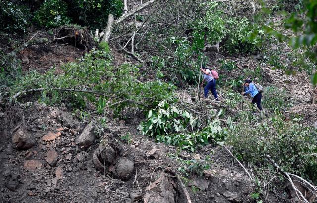 Locals walk over a landslide on the Tenango de Doria–San Bartolo Tutotepec road after heavy rains caused severe damage in Hidalgo state, Mexico, on October 13, 2025. The death toll from flooding in central and eastern Mexico -mostly in the Veracruz, Hidalgo and Puebla states- has risen sharply to at least 64, with another 65 still missing, authorities reported. (Photo by Alfredo ESTRELLA / AFP)