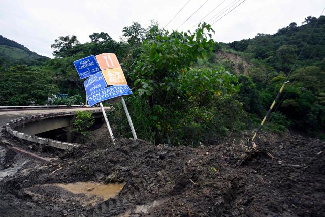 A road sign stands tilted after a landslide hit the Tenango de Doria–San Bartolo Tutotepec road in Hidalgo state, Mexico, on October 13, 2025. The death toll from flooding in central and eastern Mexico -mostly in the Veracruz, Hidalgo and Puebla states- has risen sharply to at least 64, with another 65 still missing, authorities reported. (Photo by Alfredo ESTRELLA / AFP)