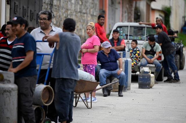 People queue to refill their cooking gas tanks after heavy rains in San Bartolo Tutotepec, Hidalgo state, Mexico, on October 13, 2025. The death toll from flooding in central and eastern Mexico -mostly in the Veracruz, Hidalgo and Puebla states- has risen sharply to at least 64, with another 65 still missing, authorities reported. (Photo by Alfredo ESTRELLA / AFP)