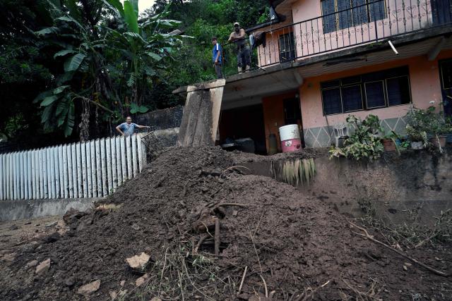 Locals look at a landslide from their rain-damaged home in San Bartolo Tutotepec, Hidalgo state, Mexico, on October 13, 2025. The death toll from flooding in central and eastern Mexico -mostly in the Veracruz, Hidalgo and Puebla states- has risen sharply to at least 64, with another 65 still missing, authorities reported. (Photo by Alfredo ESTRELLA / AFP)