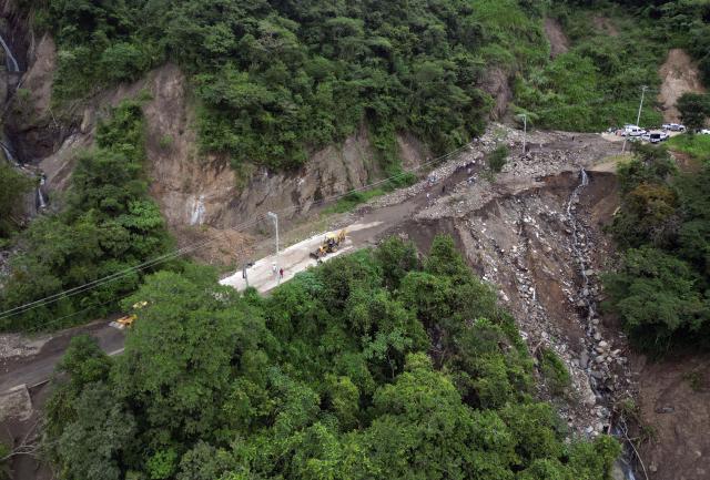 This aerial view shows residents cleaning up and removing mud after a landslide at the entrance to the town of San Bartolo Tutotepec in Hidalgo state, Mexico, on October 13, 2025. The death toll from flooding in central and eastern Mexico -mostly in the Veracruz, Hidalgo and Puebla states- has risen sharply to at least 64, with another 65 still missing, authorities reported. (Photo by Alfredo ESTRELLA / AFP)