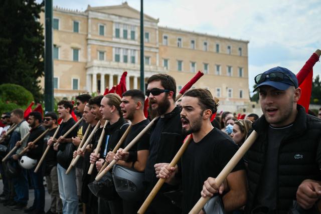 Protestors shout slogans as they gather near the Greek Parliament to take part in a demonstration during a 24-hour strike against government plans introducing an optional 13-hour workday, in Athens on October 14, 2025. Transport and services in Greece were disrupted on October 14, 2025 for the second time this month as the mobilisation will shut down public and municipal services and paralyse ferries and trains, but flights are unaffected. (Photo by Aris MESSINIS / AFP)