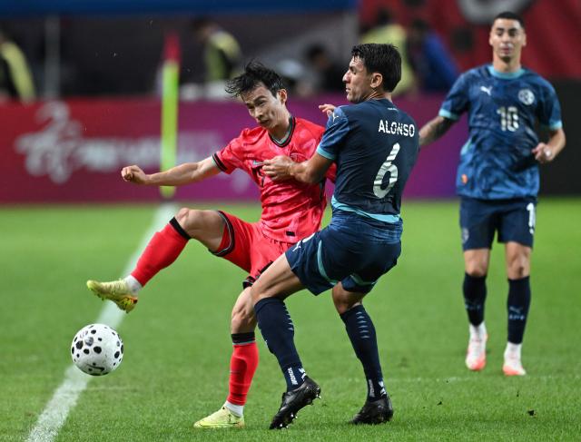 South Korea's Kim Moon-hwan (L) fights for the ball with Paraguay's Junior Alonso (C) during a friendly football match between South Korea and Paraguay in Seoul on October 14, 2025. (Photo by Jung Yeon-je / AFP)