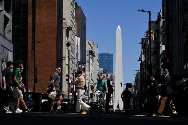 Pedestrians cross Corrientes Avenue with the Obelisk in the background in Buenos Aires on October 14, 2025. Argentina's statistics agency INDEC is expected to announce September’s inflation rate later in the day. (Photo by Luis ROBAYO / AFP)