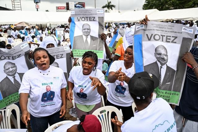 Supporters wearing T-shirts bearing the image of Democratic Congress (CODE) Presidential candidate Jean-Loui Billon dance with his posters ahead of his arrival at a campaign rally in the commune of Cocody in Abidjan on October 14, 2025. Ivory Coast Presidential election is scheduled for October 25, 2025. (Photo by Sia KAMBOU / AFP)