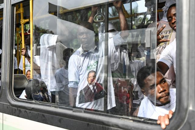 Supporters wearing T-shirts bearing the image of Democratic Congress (CODE) presidential candidate Jean-Loui Billon arrive in one of the buses for his campaign rally in the commune of Cocody in Abidjan on October 14, 2025. Ivory Coast Presidential election is scheduled for October 25, 2025. (Photo by Sia KAMBOU / AFP)