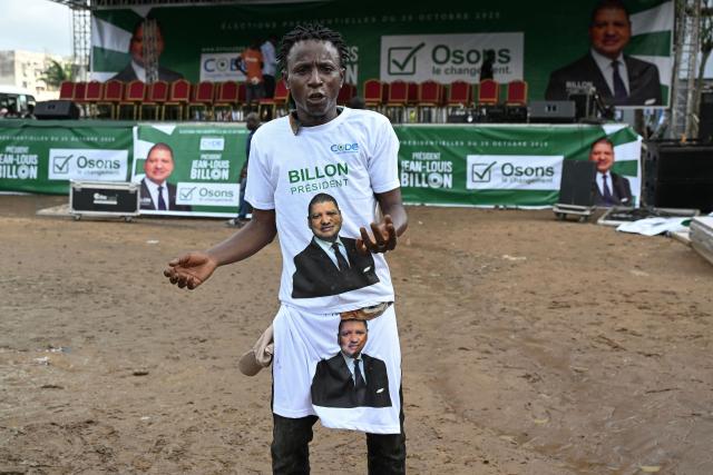 A supporter wearing T-shirts bearing the image of Democratic Congress (CODE) presidential candidate Jean-Loui Billon dances before his arrival for acampaign rally in the commune of Cocody in Abidjan on October 14, 2025. Ivory Coast Presidential election is scheduled for October 25, 2025. (Photo by Sia KAMBOU / AFP)