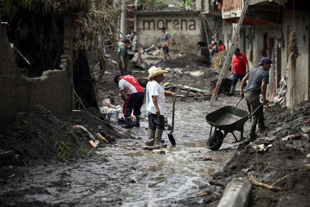 People remove the mud after severe flooding hit the town of Huehuetla,, in Hidalgo state, Mexico on October 14, 2025. Rescuers scrambled on October 13, 2025, to reach people cut off by devastating floods that have claimed 64 lives in central and eastern Mexico, with another 65 people reported missing. (Photo by Alfredo ESTRELLA / AFP)