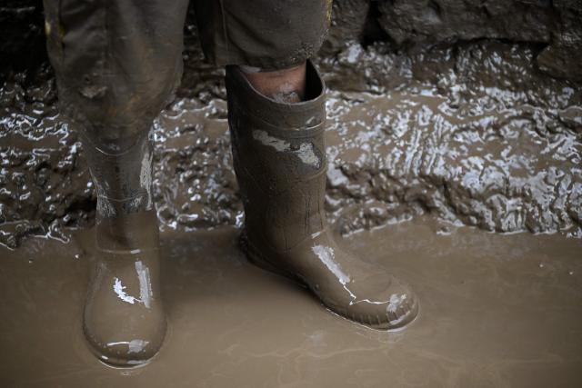 A man wades through mud after severe flooding hit the town of Huehuetla in Hidalgo state, Mexico, on October 14, 2025. Rescuers scrambled on October 13, 2025, to reach people cut off by devastating floods that have claimed 64 lives in central and eastern Mexico, with another 65 people reported missing. (Photo by Alfredo ESTRELLA / AFP)