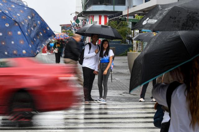 A couple with an umbrella protects themselves from the rain in San Jose on October 14, 2025. (Photo by EZEQUIEL BECERRA / AFP)