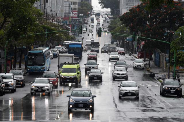 Vehicles drive through the rain on an avenue in San Jose on October 14, 2025. (Photo by EZEQUIEL BECERRA / AFP)
