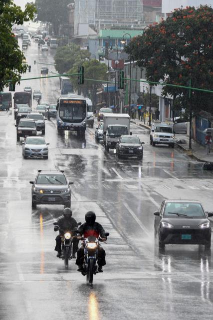 Vehicles drive through the rain on an avenue in San Jose on October 14, 2025. (Photo by EZEQUIEL BECERRA / AFP)