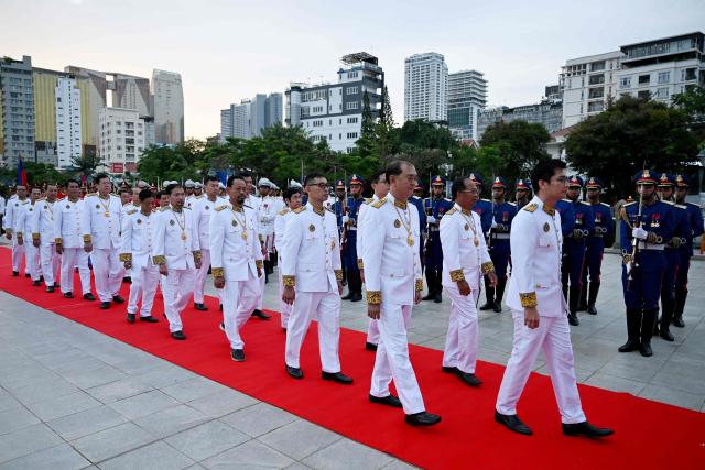 Members of the National Election Committee (NEC) walk past honour guards as they pay their respects in front of the monument of the late king Norodom Sihanouk during a ceremony commemorating his thirteenth death anniversary in Phnom Penh on October 15, 2025. (Photo by TANG CHHIN Sothy / AFP)