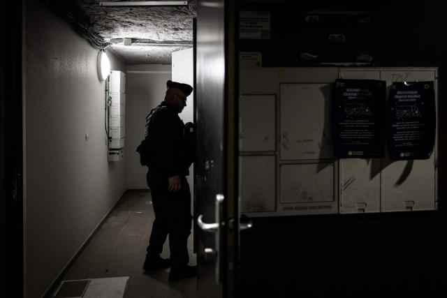 A French Republican Security Corps (CRS - Compagnies républicaines de sécurité) police officer examines a building's entrance in the Mistral neighbourhood, as part of an anti-drug operation, in Grenoble, on October 15, 2025. (Photo by JEFF PACHOUD / AFP)