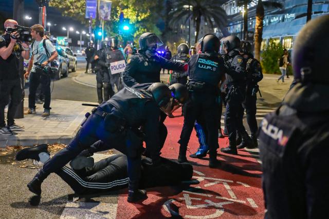 Police apprehend a protester as scuffles between protesters and police broke out during a demonstration against the participation of Israeli basketball team Hapoel IBI Tel-Aviv in the Euroleague, ahead of their match against Valencia Basket, in Valencia, on October 15, 2025. (Photo by Jose JORDAN / AFP)